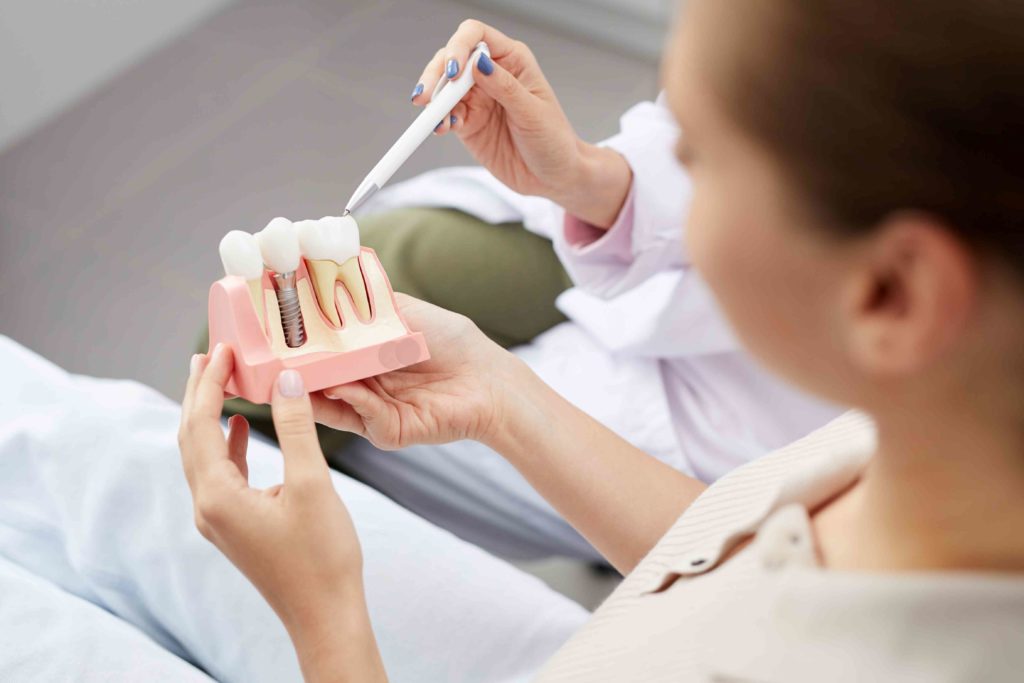 a patient looking at dental implants model while a doctor is explaining